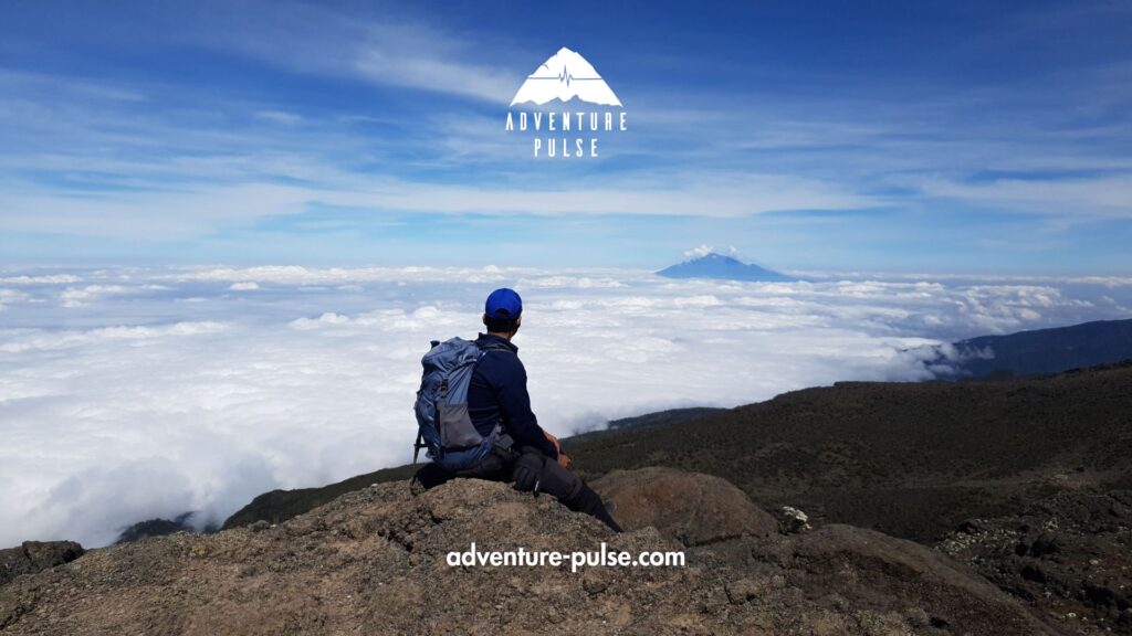 A trekker sitting on a cliff on Kilimanjaro trek