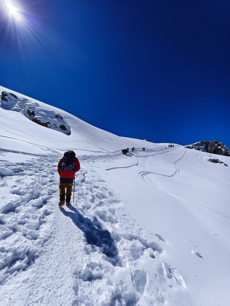 A climber walking through snow glacier on the Mera Peak